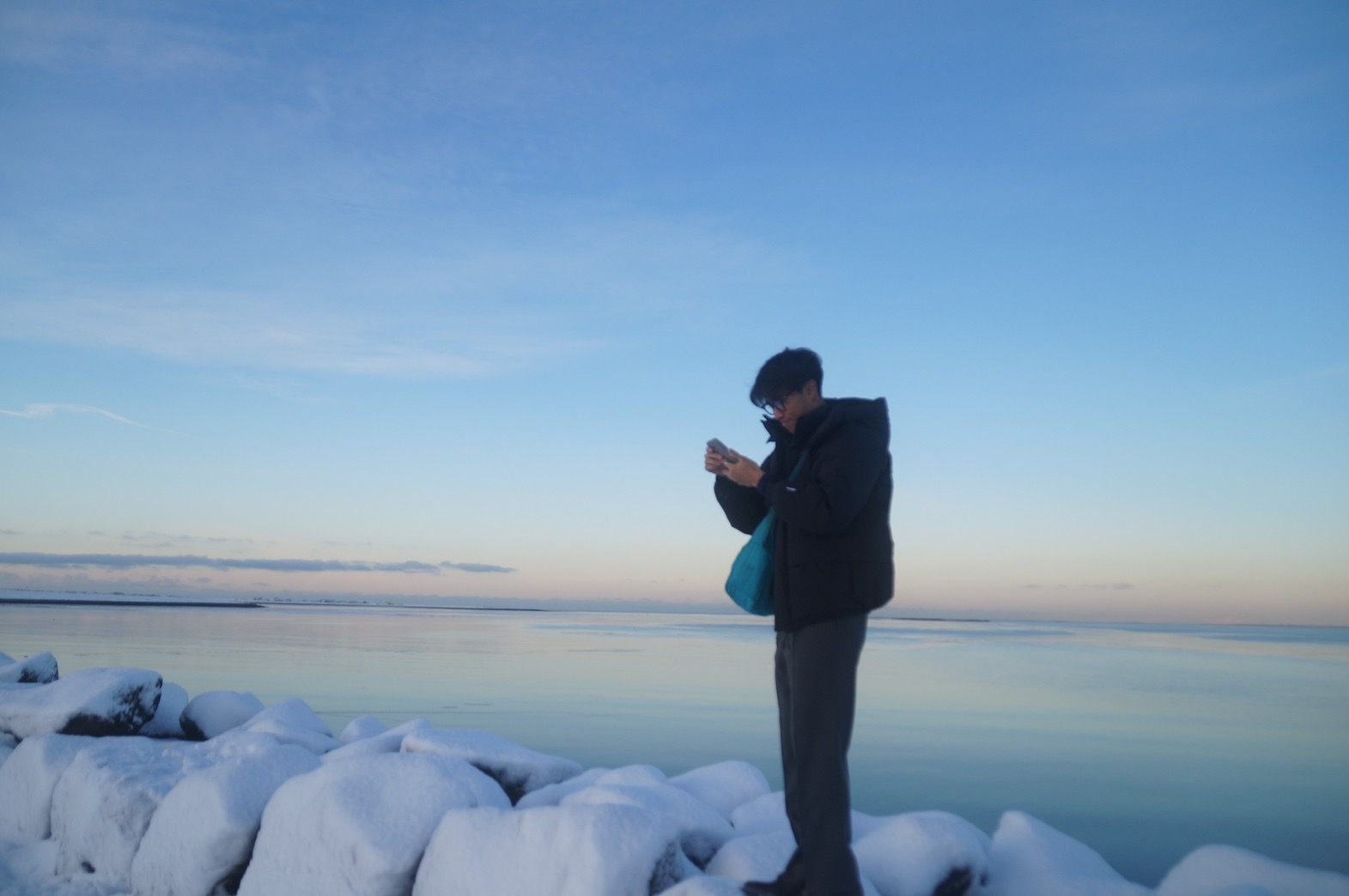 凍った海辺の岩の上で写真を撮る